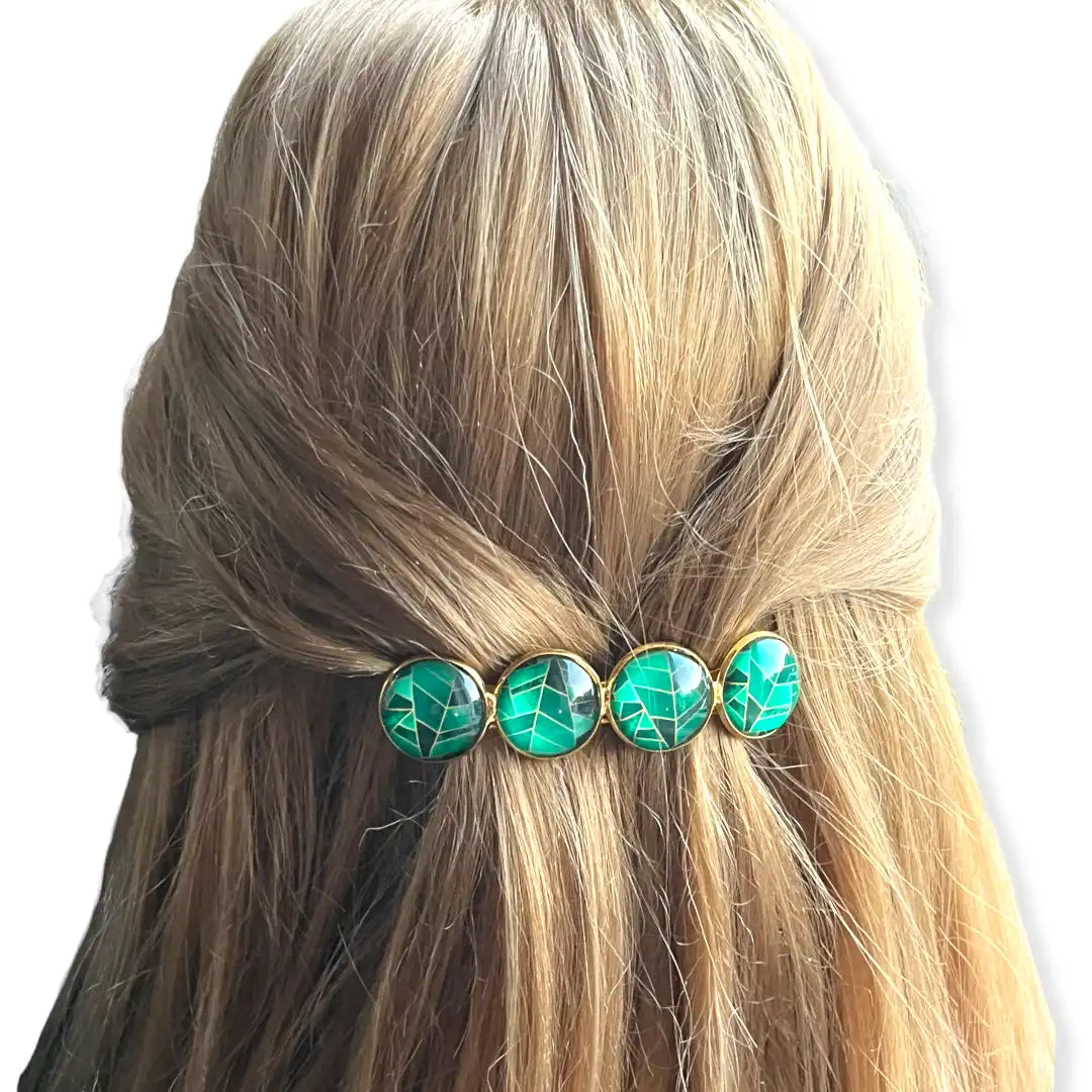 Blond haar gestyled met een vier-steen groene en gouden haarspeld.