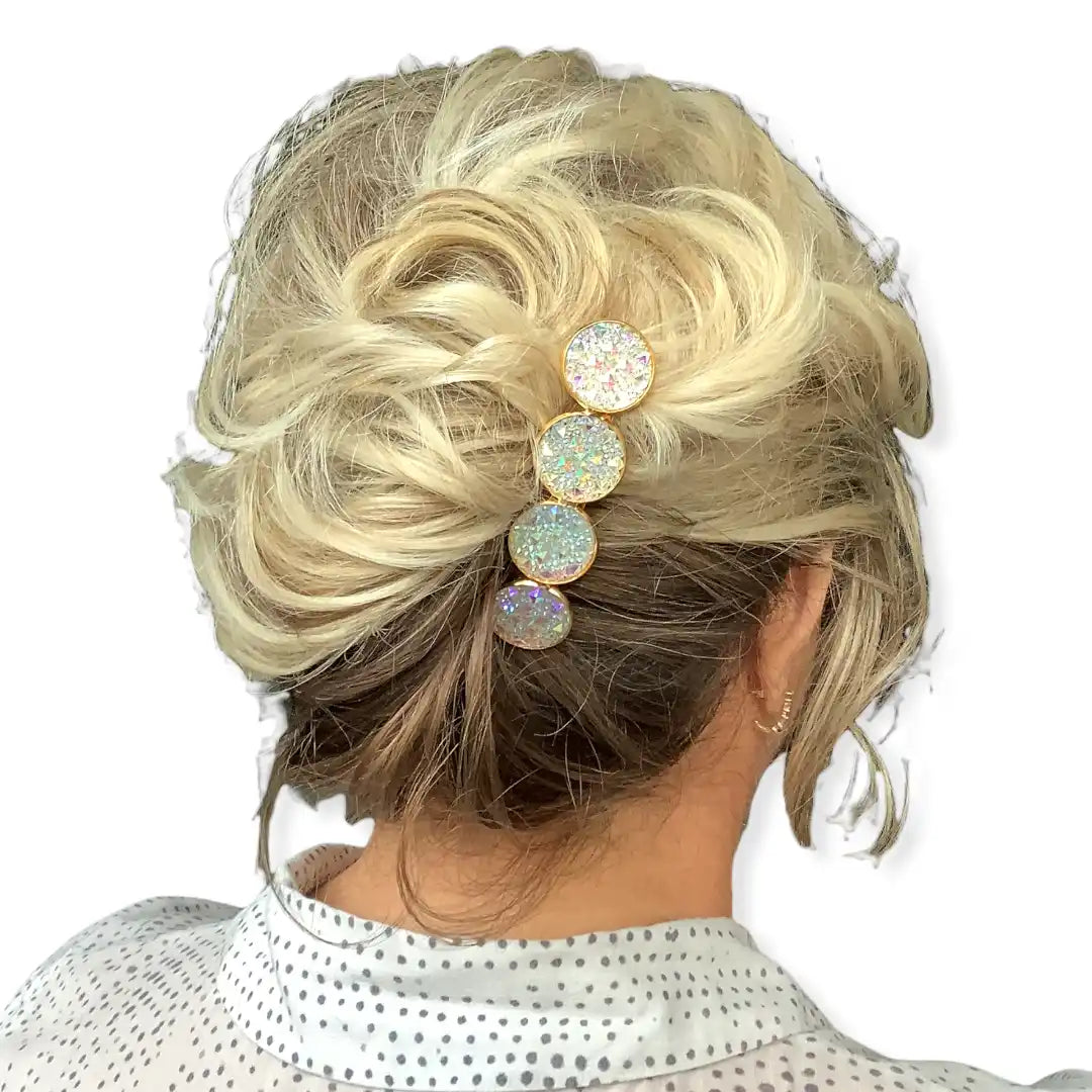 Blond haar in een opgestoken kapsel, versierd met een verticale rij van vier glanzende, ronde haarspelden.