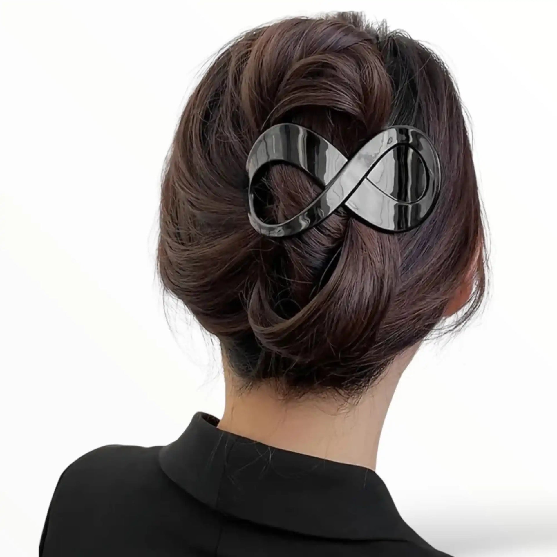 Donkere bruin haar in een dot en klaar, vastgezet met een zwart infinity symbool haarclip