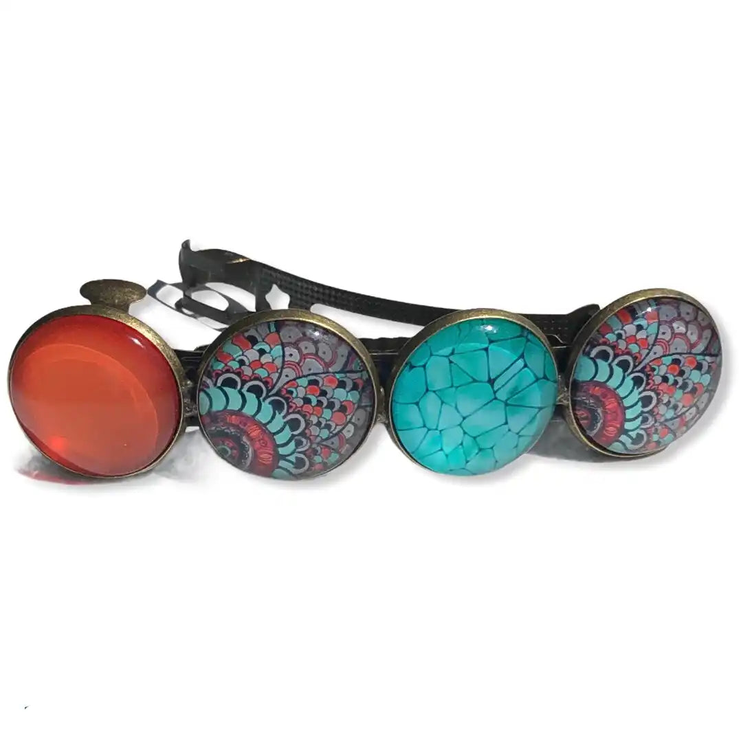 Een haarspeld met vier ronde, decoratieve cabochons: één oranje, één turquoise, en twee met een teal en roze ontworpen patroon, gezet in bronzenedelen op een zwarte ondergrond.