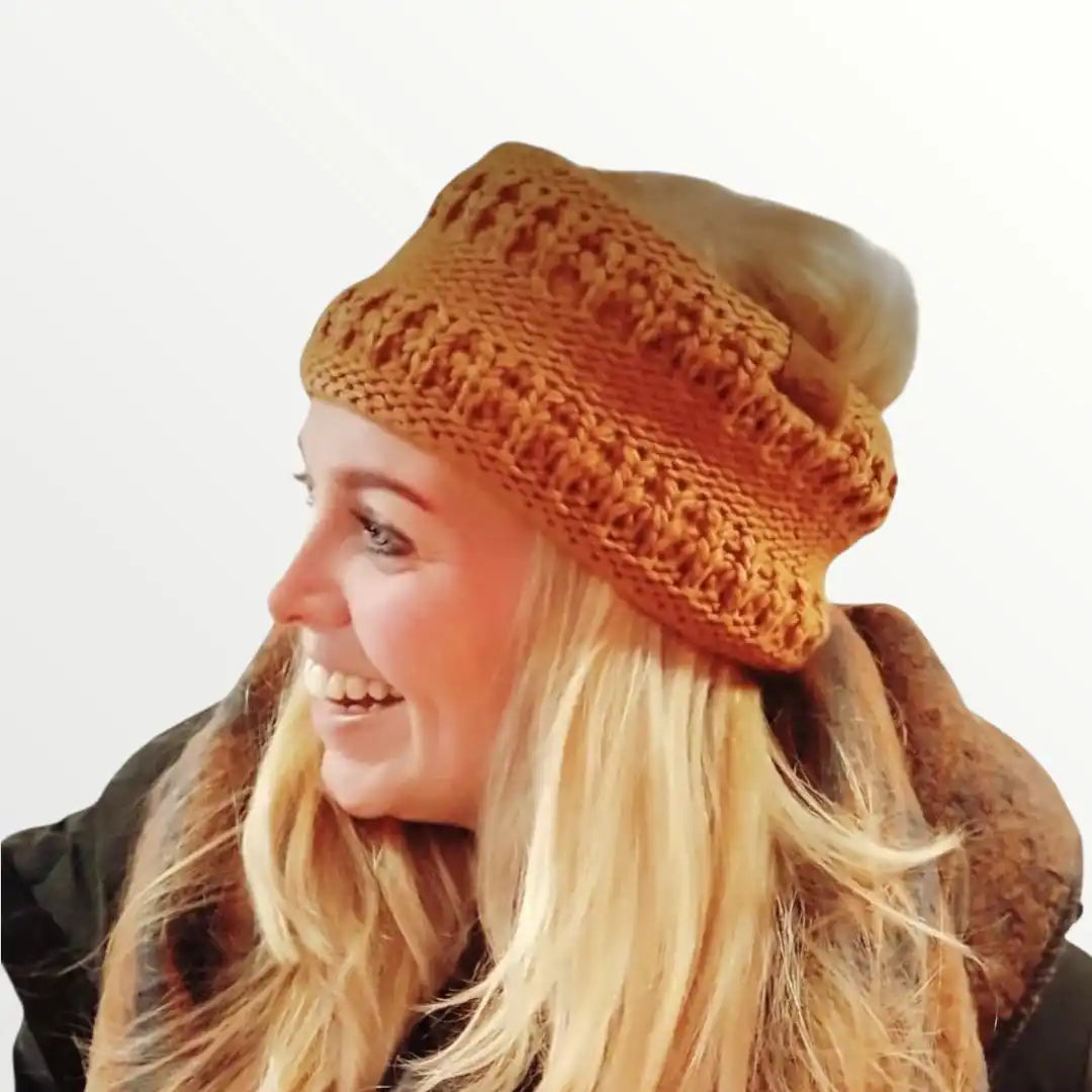 Een vrouw die een gebreide oranje muts en een bruine sjaal draagt